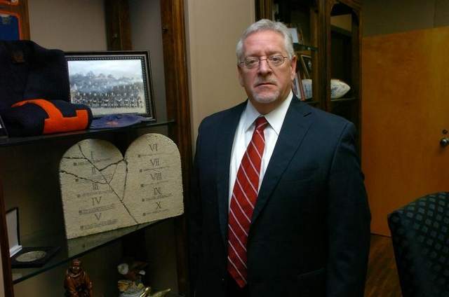 The Louisiana College Board of Trustees Needs a Cricket in their Life. Dr. Joe Aguillard in his office standing next to a 10 commantments plaque