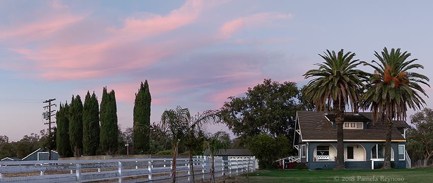 Seeing God when our metaphors fail A two story circa 1890's ranch house is shown at the end of a long driveway lined with white fencing at sunset.