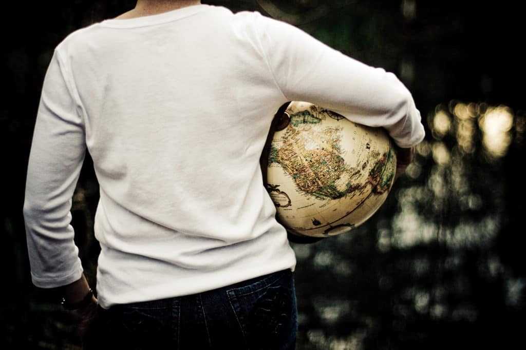You cannot save the world, but you can do your part The torso of a person is seen from the back and they are holding a globe under an arm.