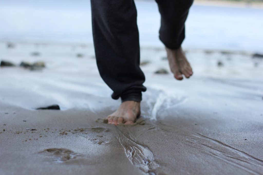 My faith won’t go barefoot: A defense of deconstruction A man's feet are seen close up running through sand at the beach.