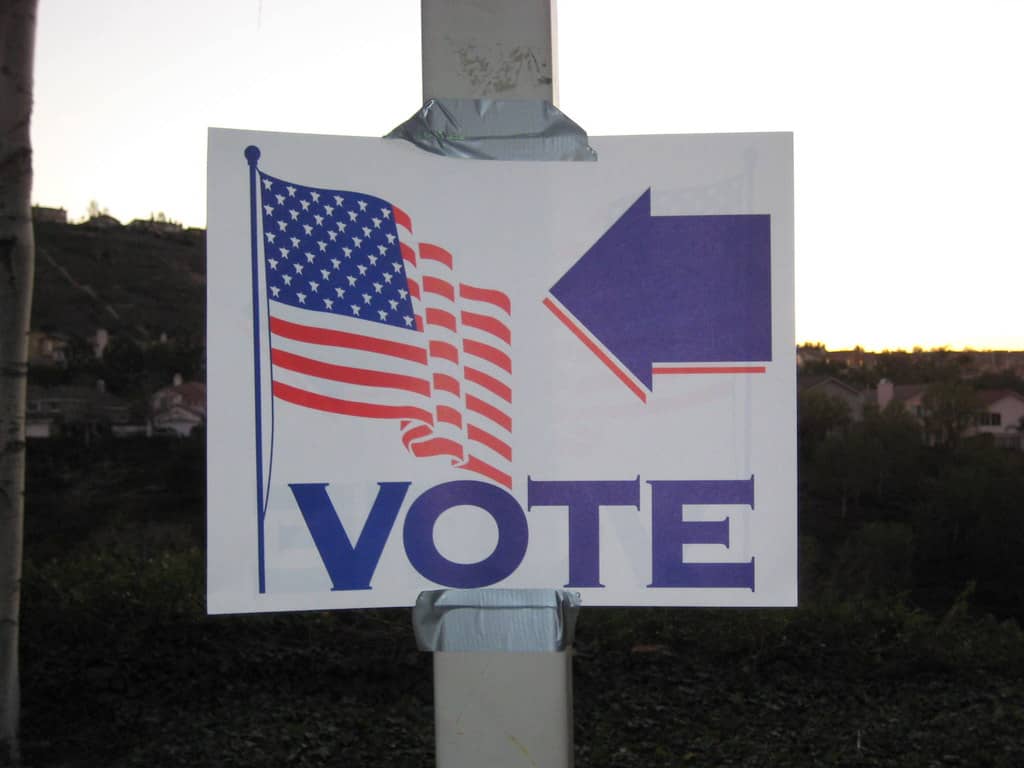 Mohler asks Christians not to vote 'wrongly’ A white sign with a blue arrow pointed toward a United States flag with the word Vote below them is taped to a pole with duct tape.