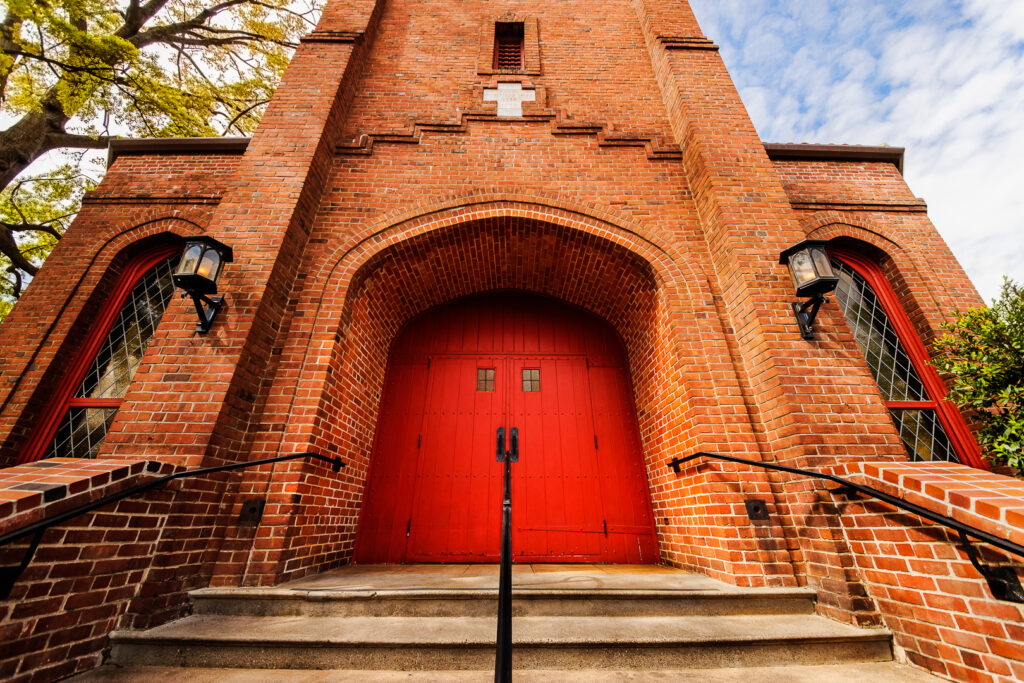 Study: More U.S. Christians may be leaving faith than joining An old red brick church building with red double doors, a white stone cross above them and matching leaded clear glass windows sits at the top of cement stairs in Chico, California, photographed by Pamela Reynoso