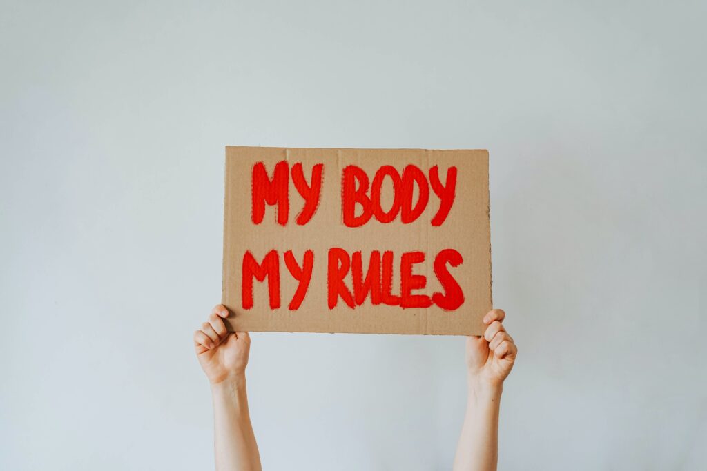 Michigan man shoots elderly pro-life canvasser A woman's hands hold up a cardboard sign with "My body my rules" painted on it in red.