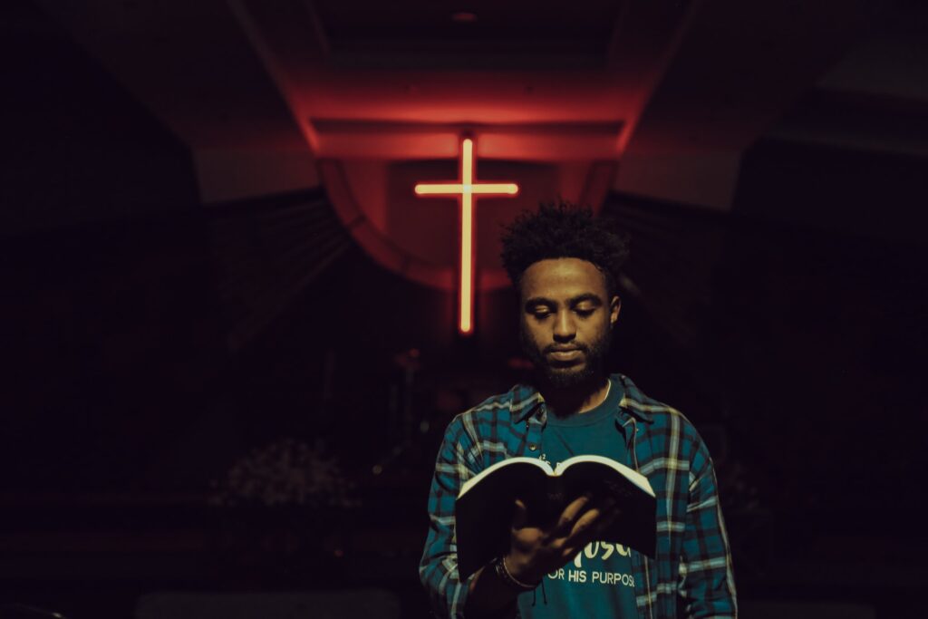 More than 60 percent of SBC church plants 'racially and ethnically diverse' A Black man wearing a flannel shirt over a t-shirt holds a softcover bible open in front of him with a neon orange cross placed up high behind him.