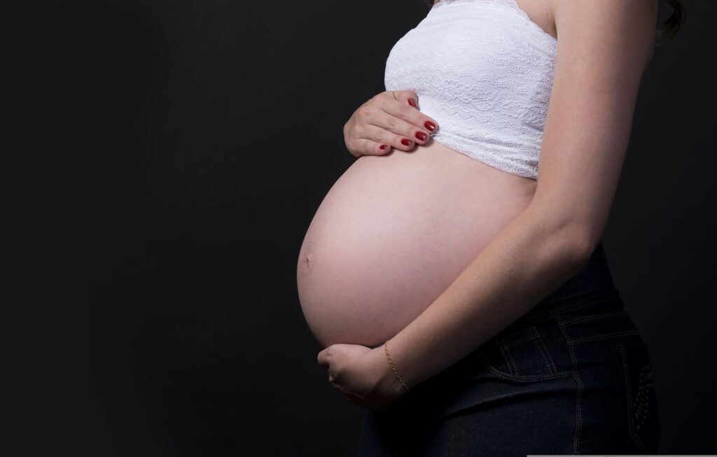 Woman believes pro-life pregnancy center saved her life A heavily pregnant woman in jeans and a white tube top is only seen from the hips to the neck holds her bare belly in a studio photo session