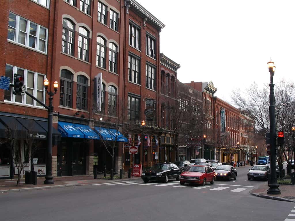 Nashville community supports barber evangelist view of a red brick old building with blue awnings from across the street.