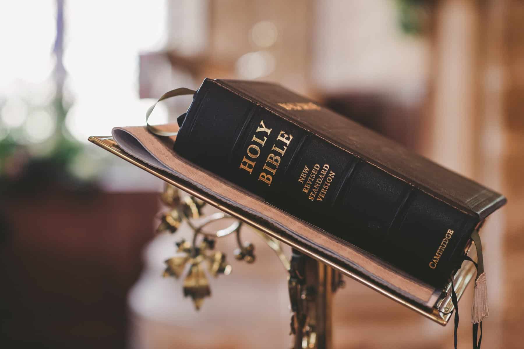 A thick bible sitting closed on a metal lectern in a church