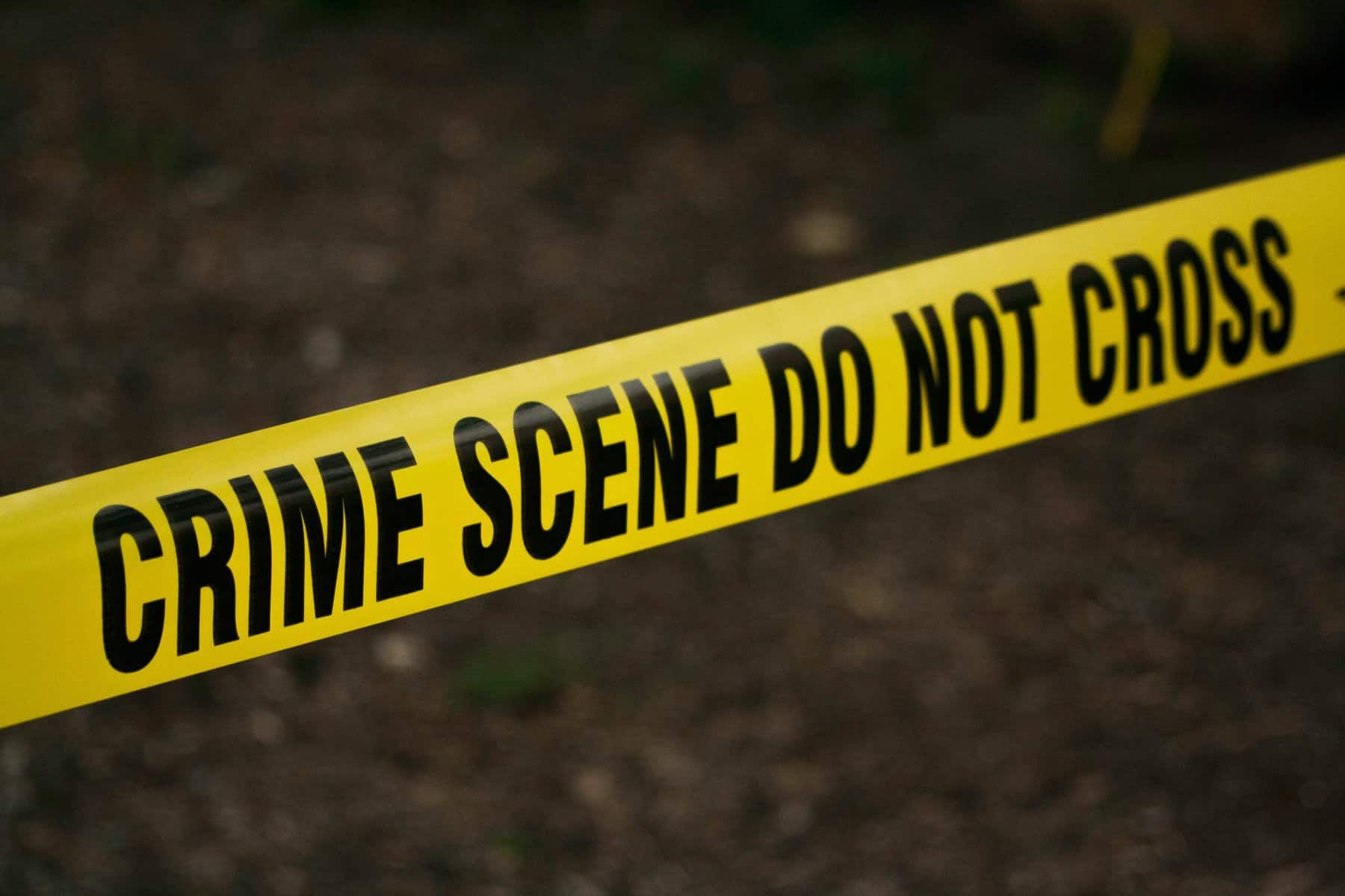 Crime scene tape stretched out over asphalt