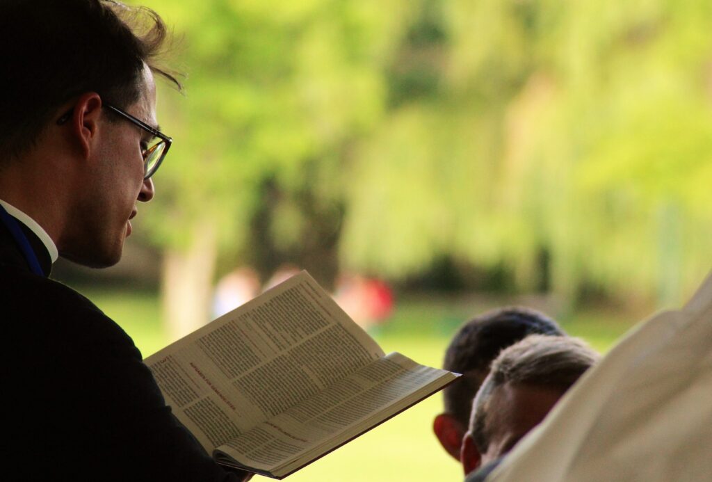Image of a preacher in a collar from the side reading the Bible