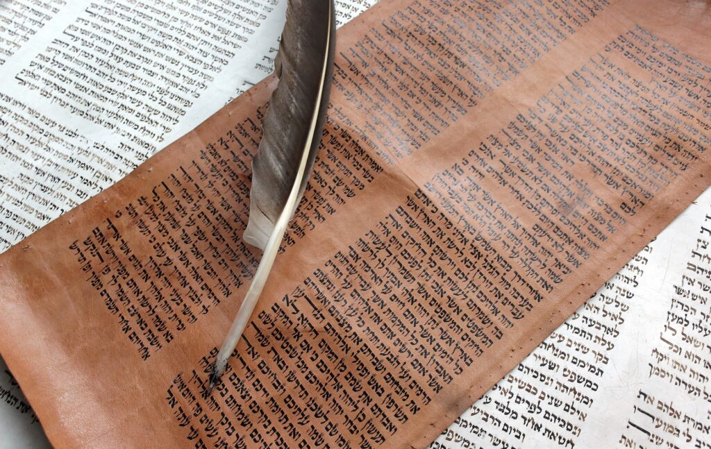 Scientists employ new method to find historical correctness of Old Testament battles A very old looking dark piece of parchment with a feather quill lays over a whitepaper with words on.