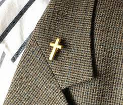 Retired chaplain prohibited from wearing cross at hospice A suit coat lapel is shown with a gold cross pin on it.