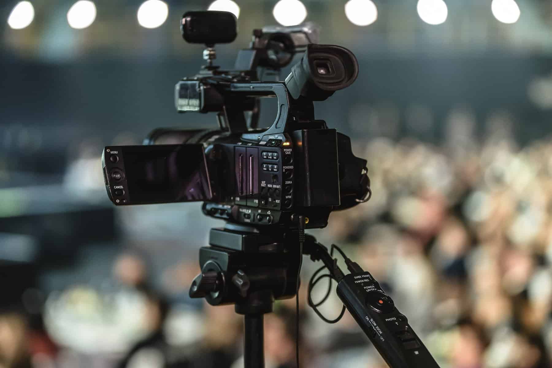 photo of a video camera as seen from the back with an out of focus crowd past it