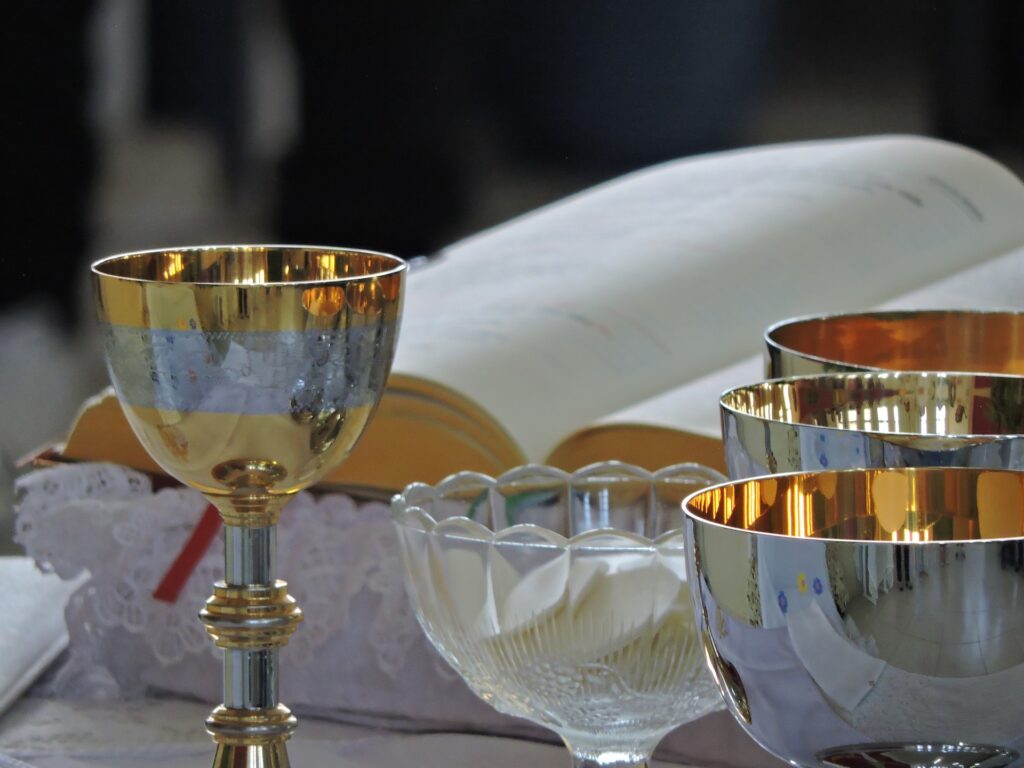 Sunday Mass again obligatory for Catholics in the Archdiocese of Chicago silver chalice, a bible, and a glass bowl with communion bread