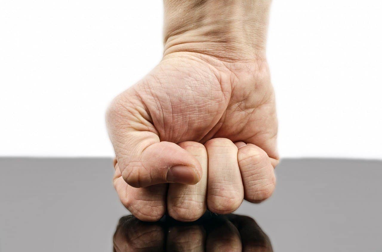 a man's fist is seen punching down on a dark glossy surfaced table