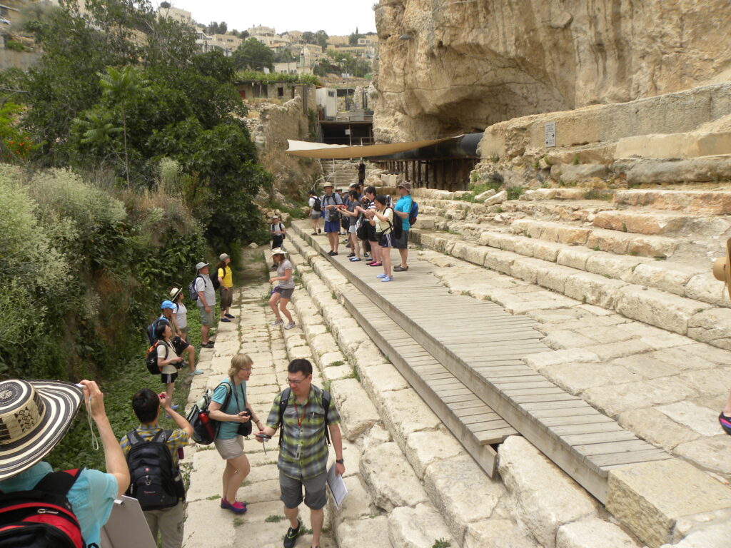 Extensive excavation planned at Pool of Siloam Tourists with hats and backpacks walk along the steps of the Pool of Siloam and take photos.