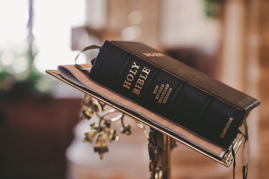 A closed black bible sits on a metal altar bookstand with the binding to the camera.