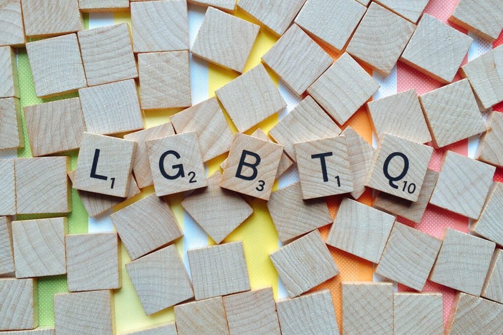 Church of England’s first gender-queer priest wishes to normalize identity among children Scrabble tiles are face down on a rainbow table with only the letters LGBTQ facing up.