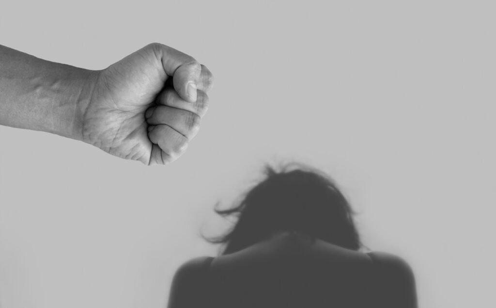Baptist woman tied and beaten by religious majority in Mexican village In this B&W image a fist is shown close to camera, a bowed head with longer hair is further away, implying violence.