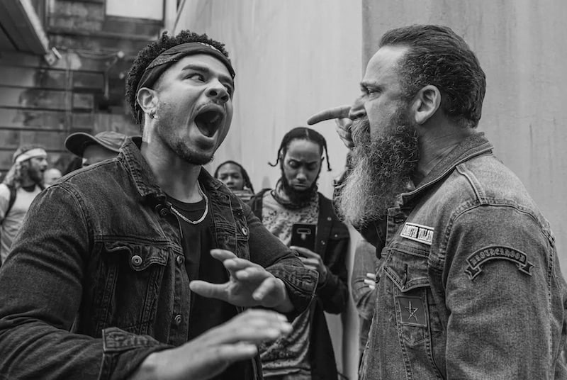 Why Does Jesus Need a PR guy? This black and white image shows two bearded men in casual clothing are shown an animated conversation.