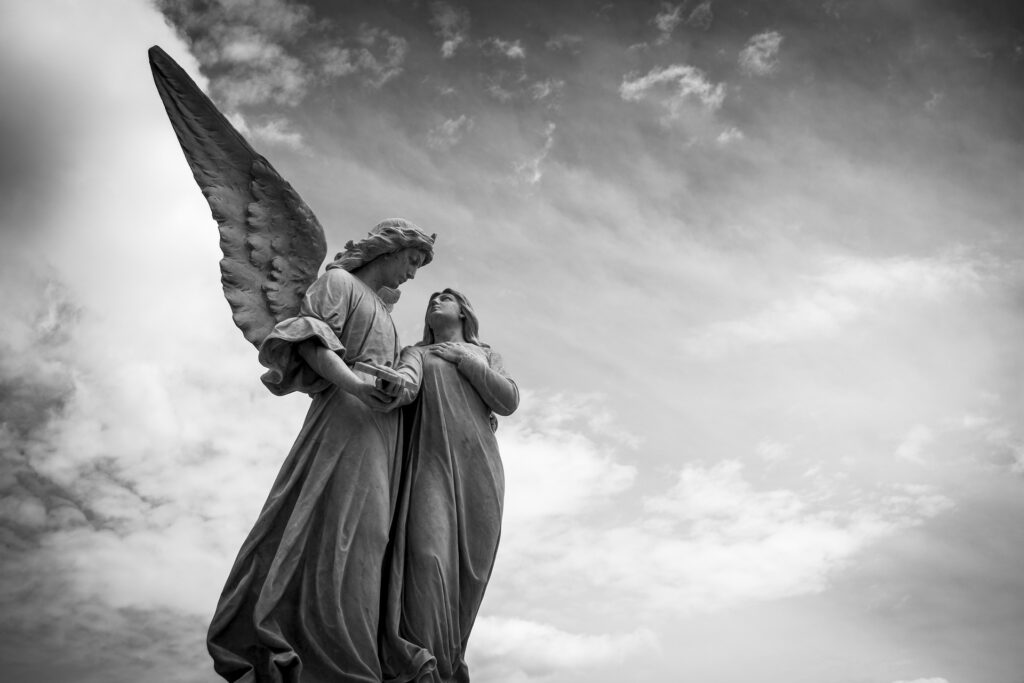 Italy sticks to promise of helping persecuted Christians This black and white image shows the statue of an angel appearing to protect a person.