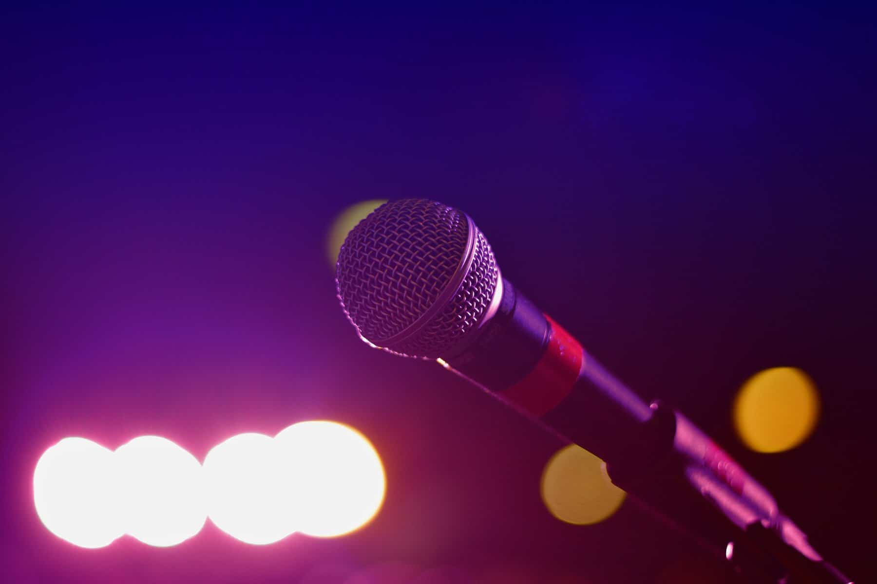A single microphone is shown under stage lighting.