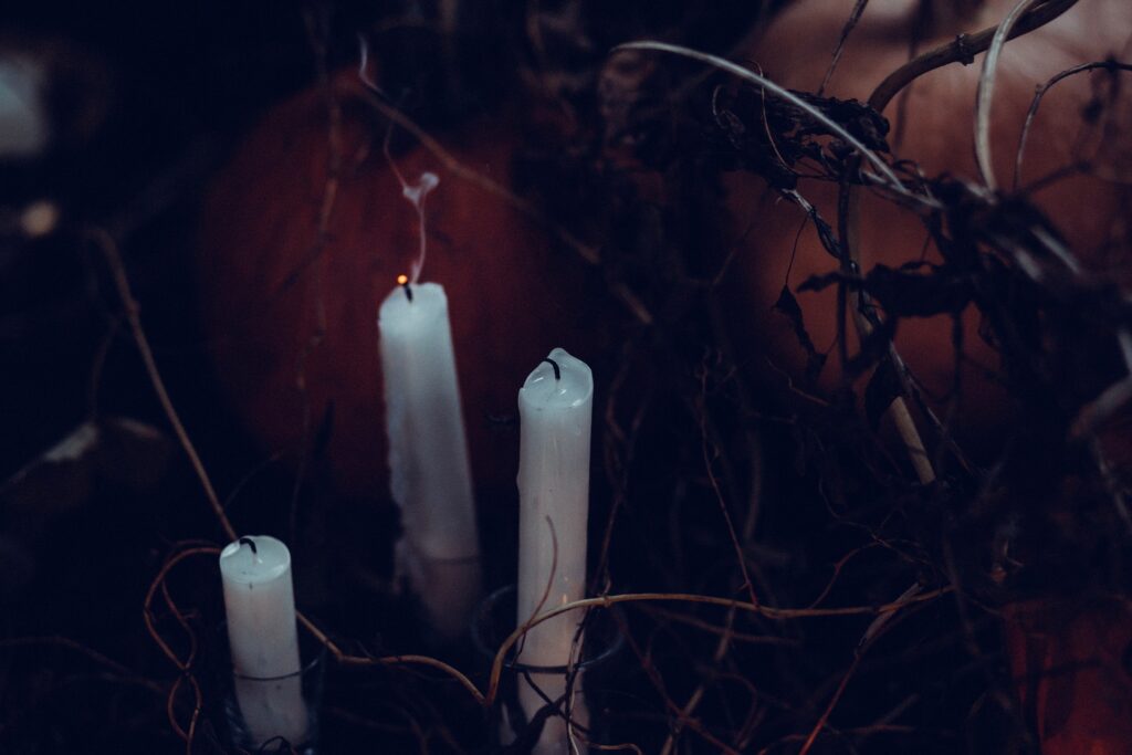 Christian podcast “The Exorcist Files” tops the charts Three white tapered candles are shown in a dark roon having just been blown out with smoke trailing from the wicks.