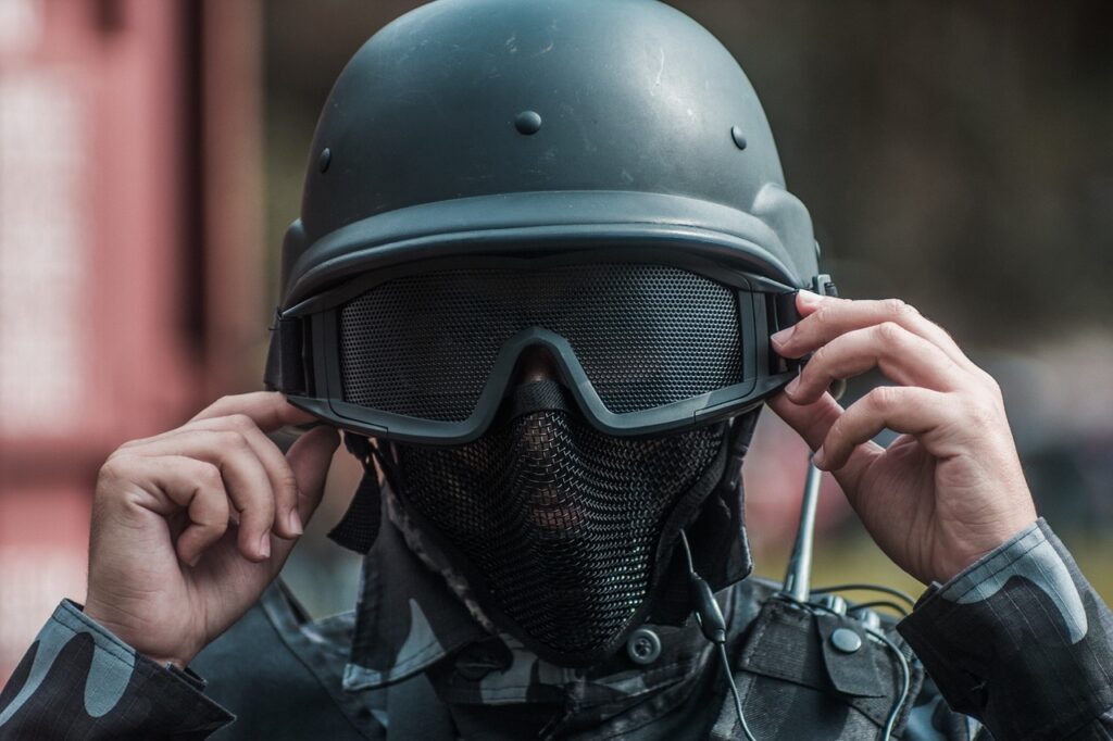 A person is shown in combat clothing and helmet with goggles.