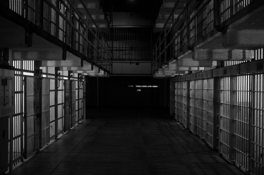 Black and white photo shows an Alcatraz type prison with cells on either side of a walkway.