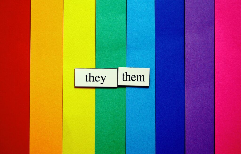 ‘Holy Queer’ author hopes for Black church inclusion Paper rainbow stripes are overlaid with two pieces of paper, one saying they, the other them.