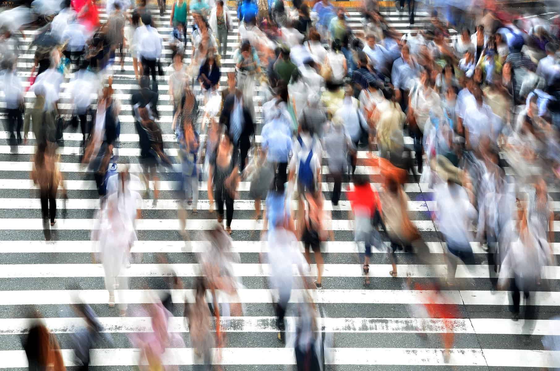 Image shows a blurred crowd ascending stone steps in daylight.