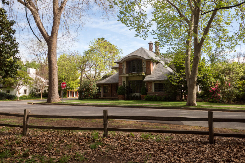A nice European style two story house with fancy brick work and wrought iron fencing is seen from the road.