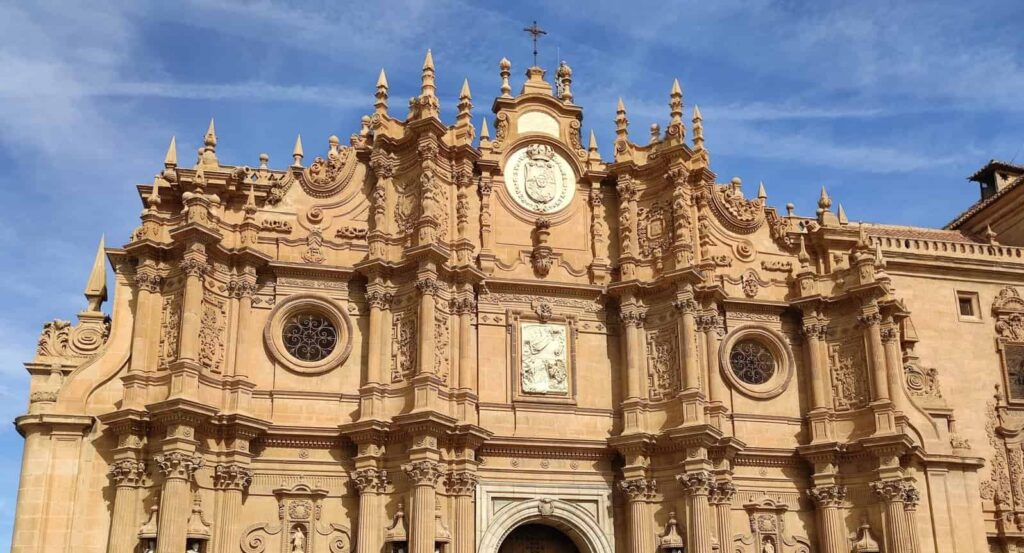 Shown from the street are the top two levels of Spain's orangish yellow Guadix Cathedral