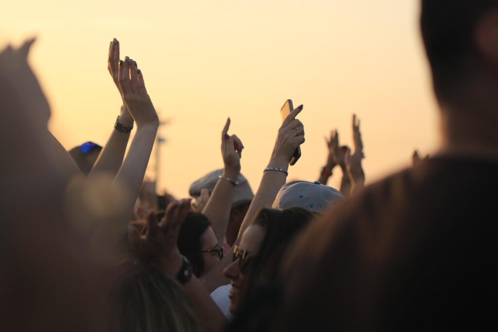 400 young people get baptized at Winterfest Many hands from a crowd are seen thrust up to the sky at dusk.