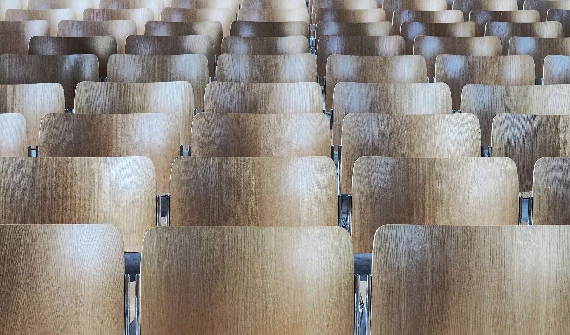 Wooden stadium seats are shown several rows deep from below.