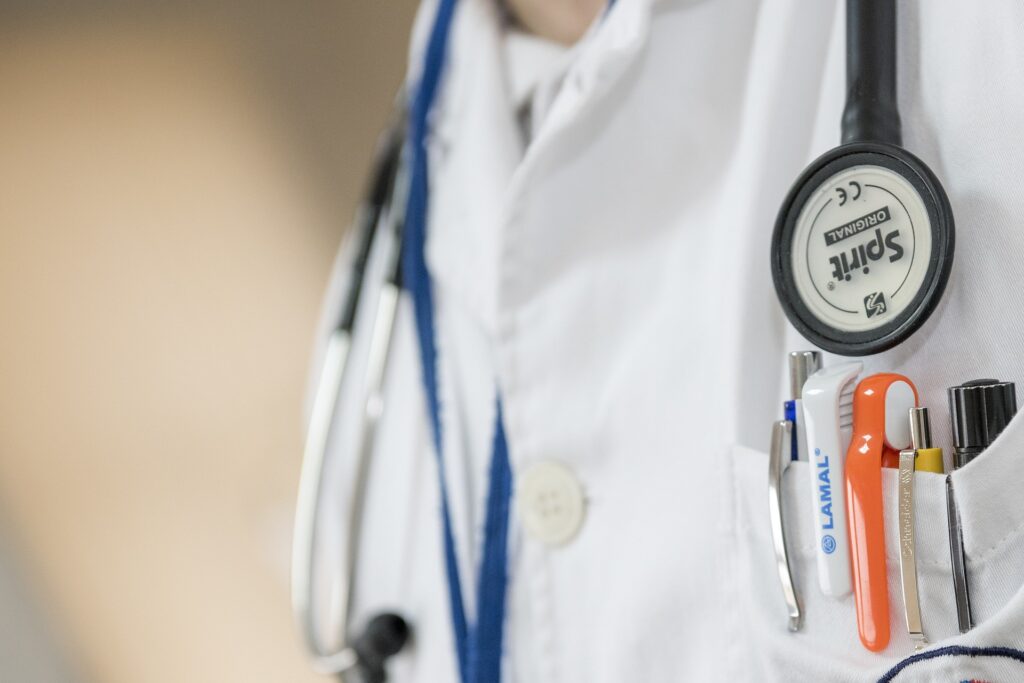 Attorneys warn about ‘legal firestorm’ over threats to Catholic hospital regarding chapel candle An extreme close up shows a medical person's white lab coat with pens in the pocket and a stethoscope around the neck.