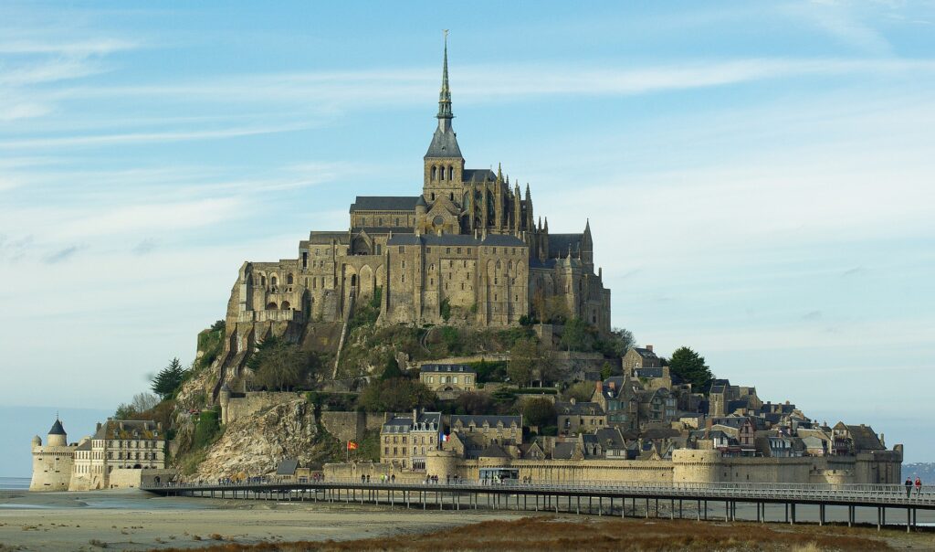 Mont Saint-Michel Abbey commemorates 1,000 years of history Mont Saint-Michel is shown from a distance with a blue sky and a smear of white clouds.