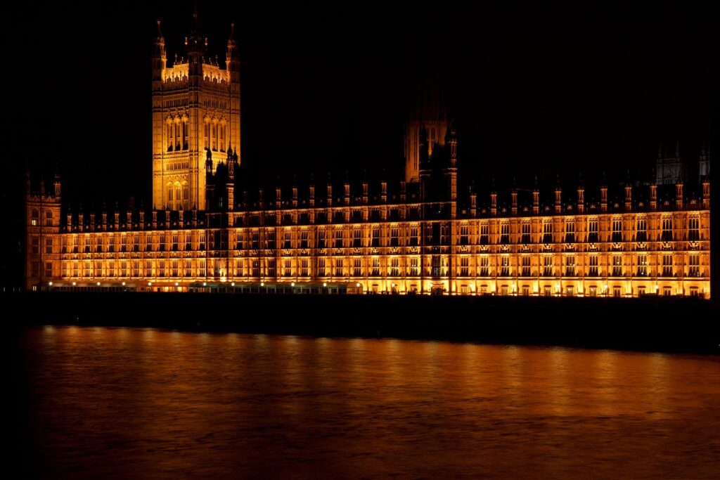UK bishops unite with interfaith leaders, denounce illegal migration bill Westminster palace bridge is shown reflecting on water at night.