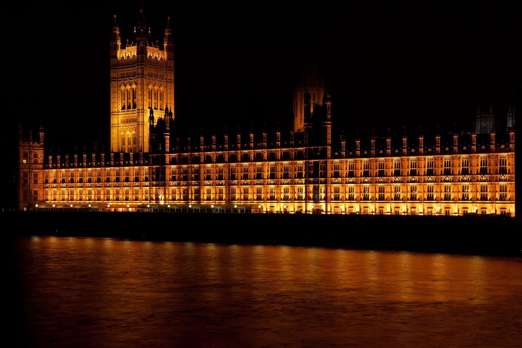 Westminster palace bridge is shown reflecting on water at night.
