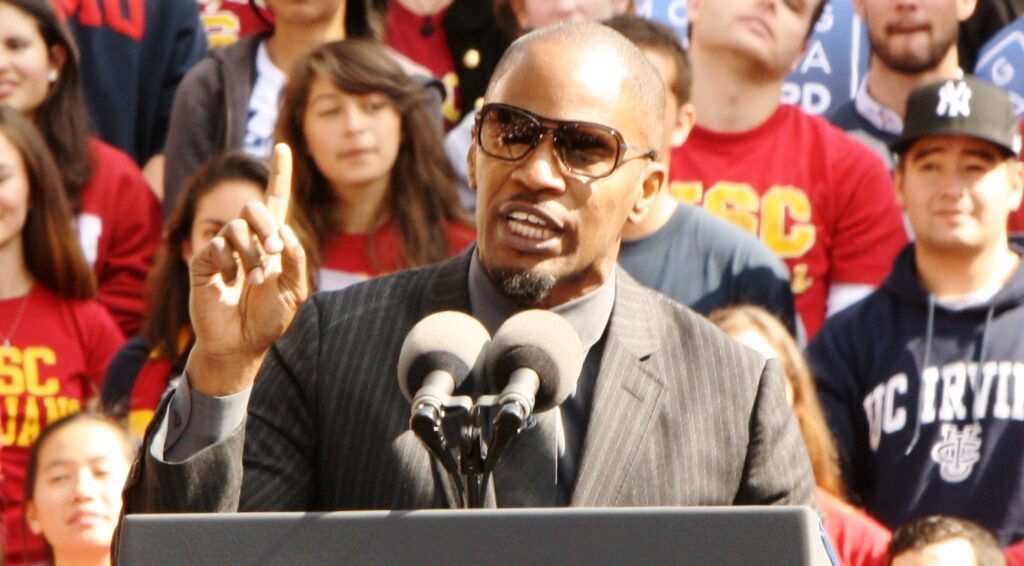 Actor Jaime Foxx stands speaking at an outdoor podium.