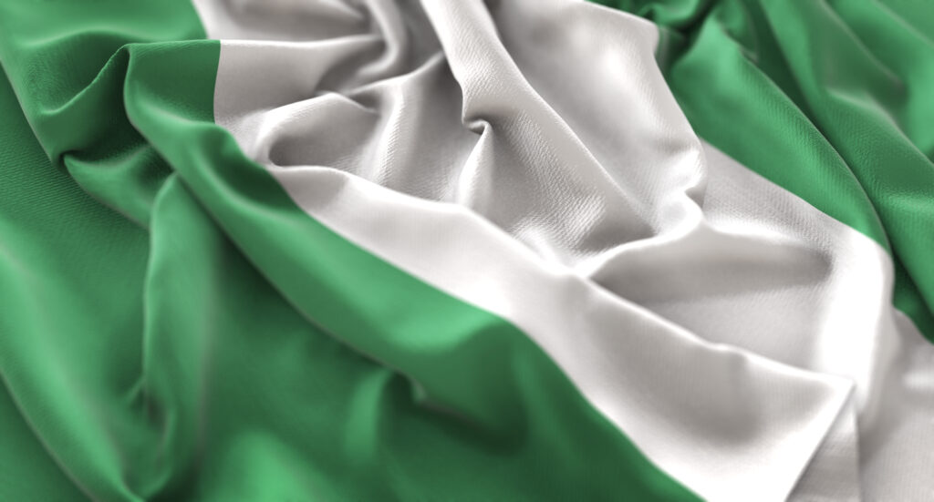 A green and white Nigerian flag is seen loosely crumpled on a flat surface.