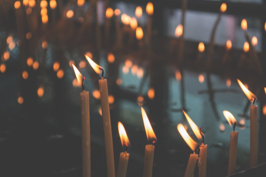 Lit tapered candles are seen in the foreground with lights twinkling behind them.