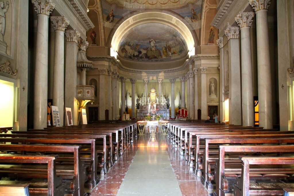 The front of an ornate church is seen from far down the aisle.