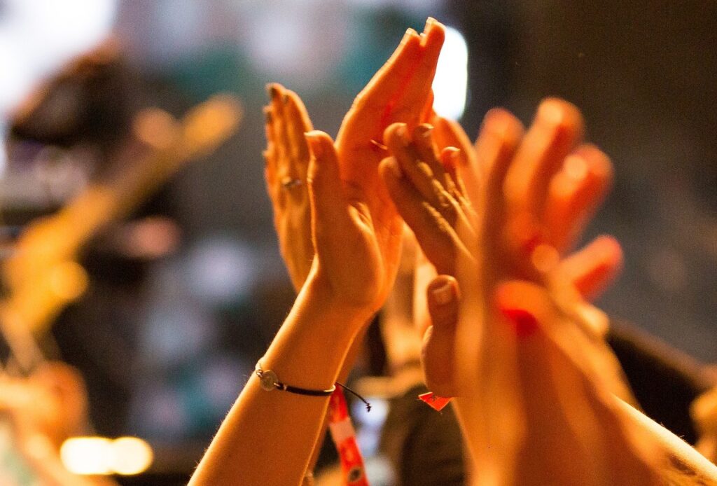 Raised hands are shown clapping.