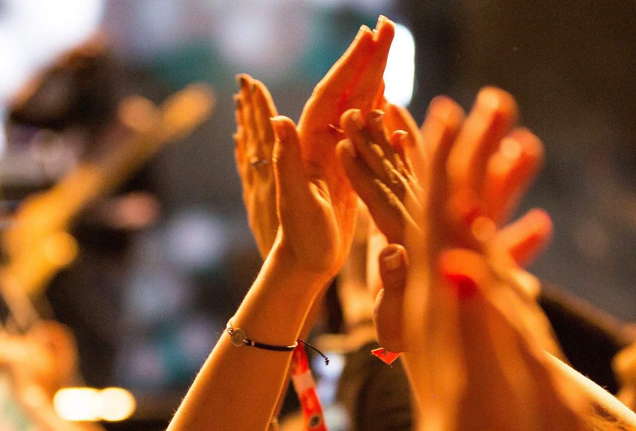 Raised hands are shown clapping.