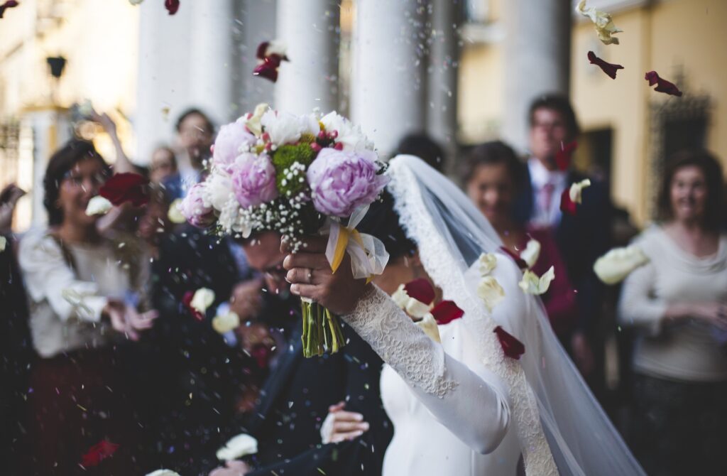Church of England to pilot free wedding services A couple is shown in a wedding photos with the bride's bouquet blocking their faces as they walk down the aisle.