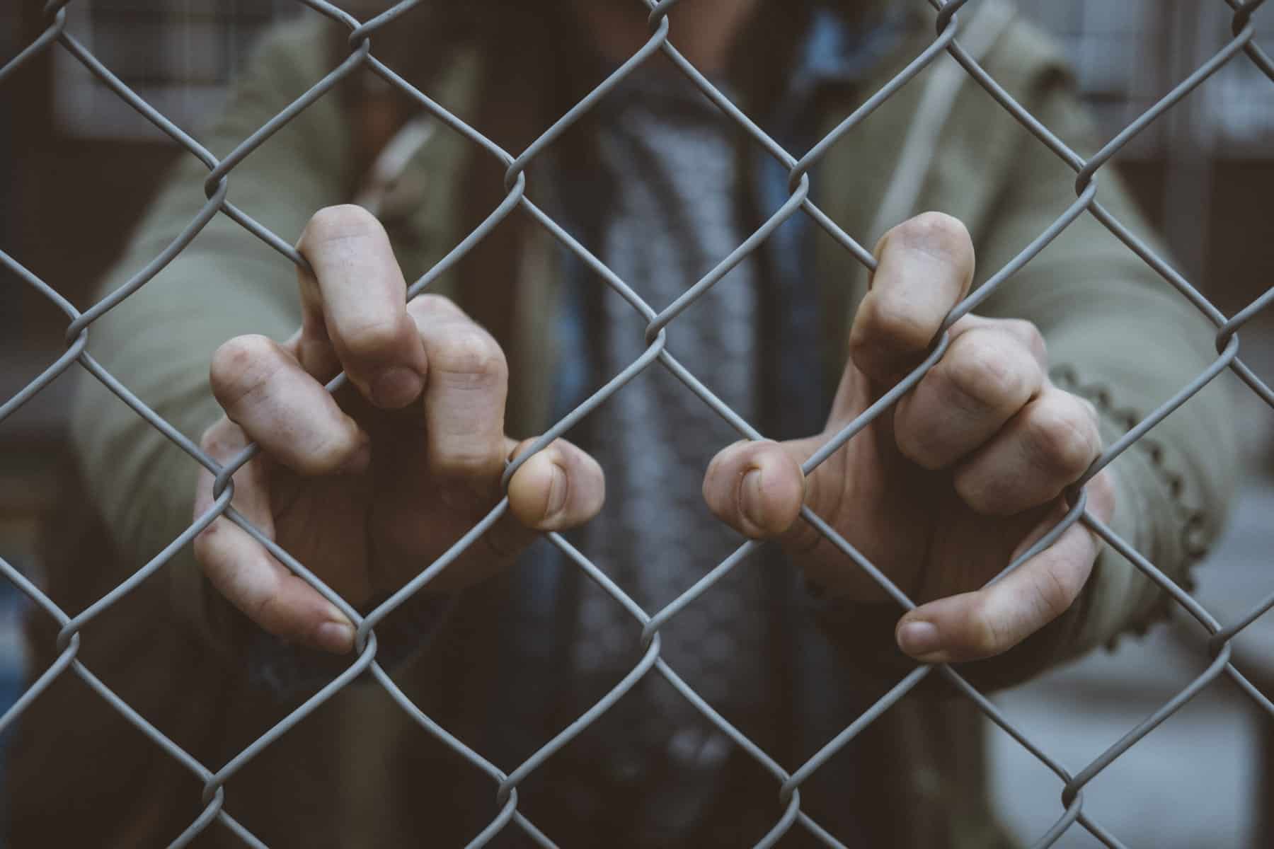 Macro view of an urban person's hand on a chain link fence