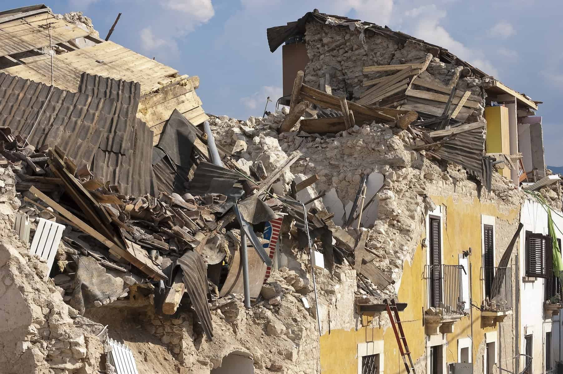 A yellow fronted stone building that has a destroyed roof and façade is shown.