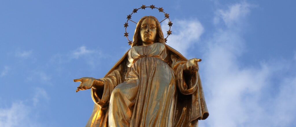 A golden statue of a saint is shown from below.