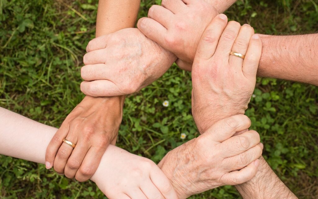 Interfaith leaders converge in Chicago to address authoritarianism Six hands are shown over grass each holding another's wrists.