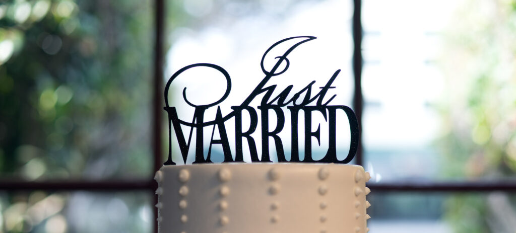 The Scam of Commercialized Christianity A white wedding cake with a black metal topper that says "Just Married".
